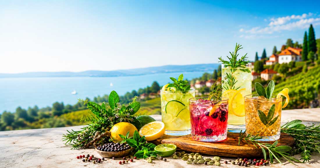 alkoholfreie Cocktails mit Rosmarin, Minze, Salbei, Zitrusfrüchten und Gewürzen vor sommerlicher Balaton-Kulisse.